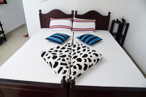 a bed with black and white sheets and pillows at Super View Home Stay in Ella