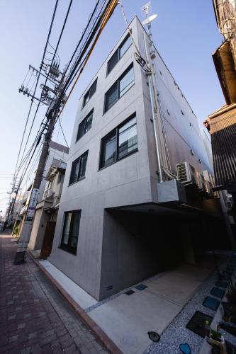 a white building with a crane on the side of it at Crecer Apartment Hotel kamata in Tokyo