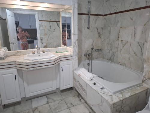 un bagno bianco con vasca e lavandino di Appartement 1 chambre Sapphire Beach a Cupecoy