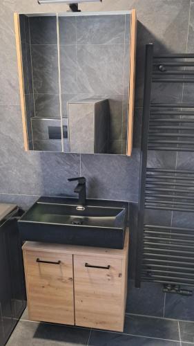 ein Badezimmer mit einem schwarzen Waschbecken und einem Spiegel in der Unterkunft Das Litzldorf in Sankt Michael im Lungau
