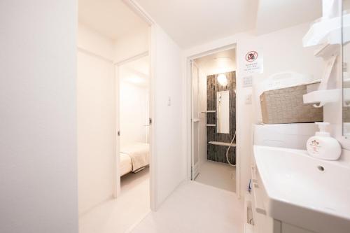 a white bathroom with a sink and a mirror at Crecer Apartment Hotel kamata in Tokyo