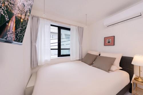 a bedroom with a white bed and a window at Crecer Apartment Hotel kamata in Tokyo