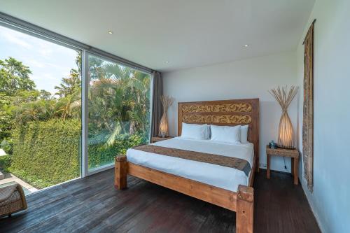 a bedroom with a bed and a large window at Villa Ashoka Canggu in Canggu