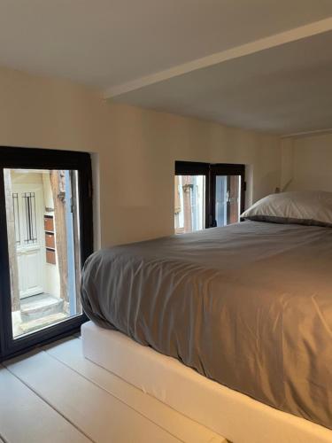 a bedroom with a bed and a large window at Duplex charmant centre Joigny - 1 in Joigny