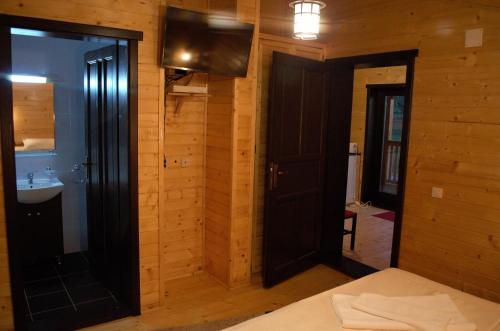 a bedroom with wooden walls and a door and a sink at Complex Agroturistic Livada de Nuci in Baia de Fier