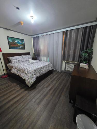 a bedroom with a bed and a desk and a window at Robinsons Place Residences Tower 1 in Sampong