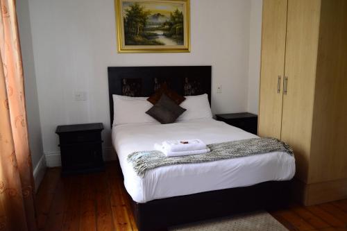 a bedroom with a large bed with white sheets at Laletsa Lodge in Durban