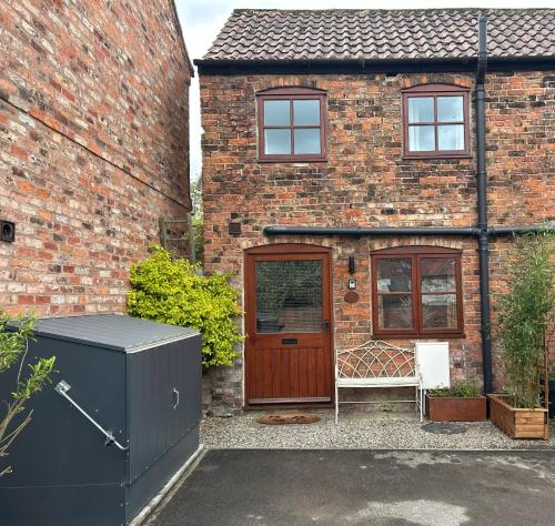 a brick house with a wooden door and a bench at 1 Bed cottage town centre free private parking cycle store Boroughbridge in Boroughbridge