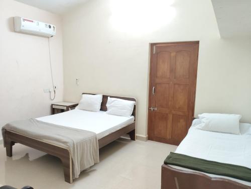 a room with two beds and a wooden door at Richnest Apartment and villas Colva in Colva