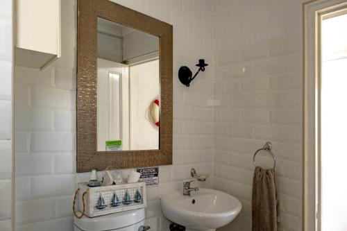 a white bathroom with a sink and a mirror at Joan's Sea Cottage in Pringle Bay