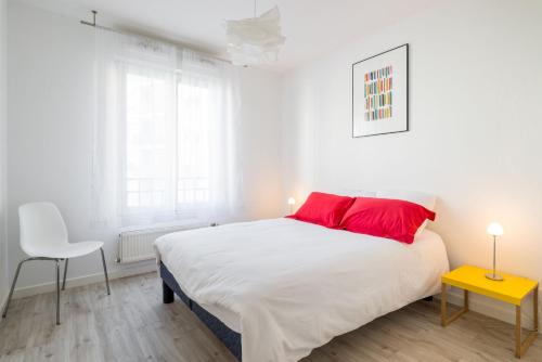 - une chambre blanche avec un grand lit et des oreillers rouges dans l'établissement T2 Part Dieu, à Lyon