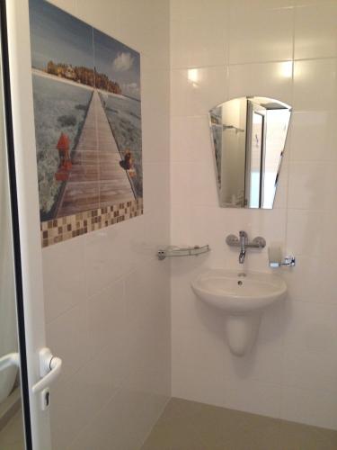 a bathroom with a sink and a mirror at Kamelot Hotel in Pasarel