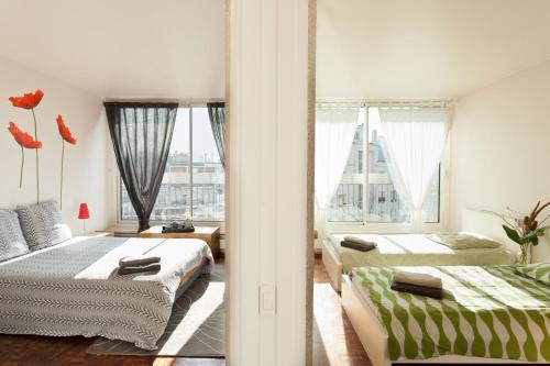 a bedroom with two beds and a large window at Appartement le Méridien in Paris