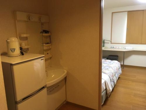 a small kitchen with a refrigerator and a bed at Hotel Tajimi Hills Myroom in Tajimi