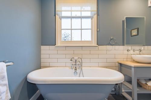 een badkamer met een bad en een wastafel bij Corner House in Deal