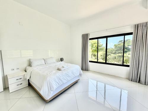 a white bedroom with a bed and a large window at Amuji Accommodation and Apartments in Vilanculos