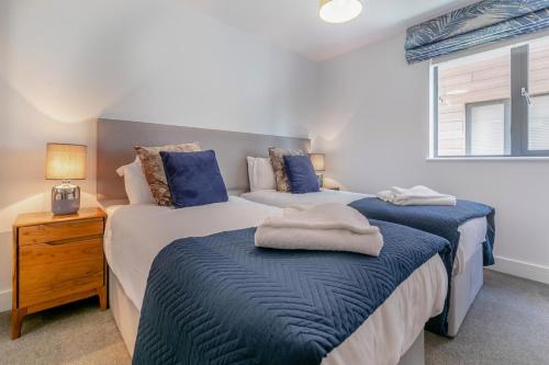 a bedroom with two beds with blue sheets and a window at 2 Bed in Woolacombe oc-c29467 in Woolacombe