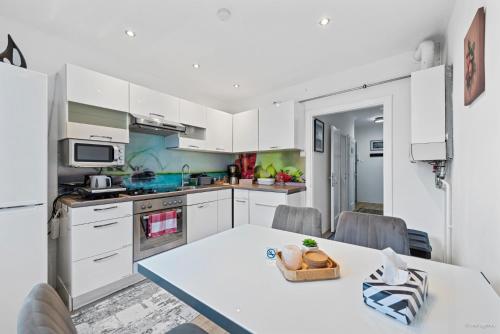 eine Küche mit weißen Schränken und einem Tisch in der Unterkunft Big 1 Bedroom Apartment near Airport & City Center in Schwechat