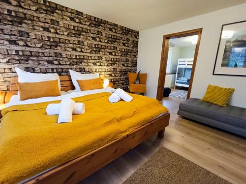 a bedroom with a yellow bed with a brick wall at Harzer Bergstadthaus für Familien und Freunde in Sankt Andreasberg