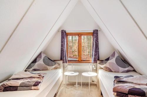 2 Betten in einem Dachzimmer mit Fenster in der Unterkunft Twistesee Ferienhaus 2 in Wetterburg