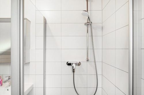 eine Dusche mit Schlauch in einem weiß gefliesten Badezimmer in der Unterkunft Twistesee Ferienhaus 2 in Wetterburg