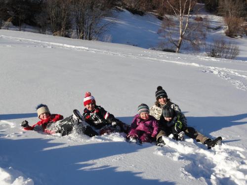 a group of children are laying in the snow at Haus Hochzeigerblick in Wenns