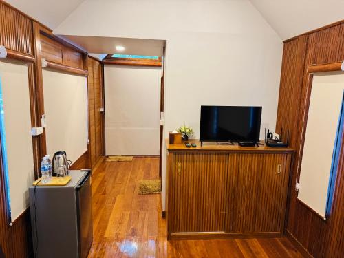 een kamer met een televisie aan een houten muur bij JJ Palace เจเจ พาเลซ in Ban Si Than