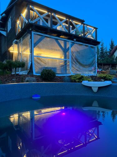 een glazen huis met 's nachts verlichting in het water bij Czerwony Kominek in Lutek