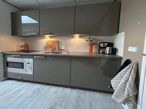 eine Küche mit Spüle und Mikrowelle in der Unterkunft Alluring Apartment in Bergen with Terrace, Garden and BBQ in Bergen