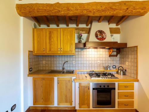a kitchen with wooden cabinets and a stove top oven at Apartment in a farmhouse with 2 swimming pools in Cagli