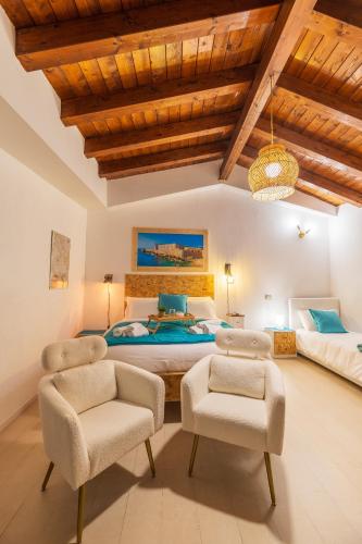 a bedroom with a large bed and two chairs at Elsa d'Ortigia - I Tre Archi in Syracuse