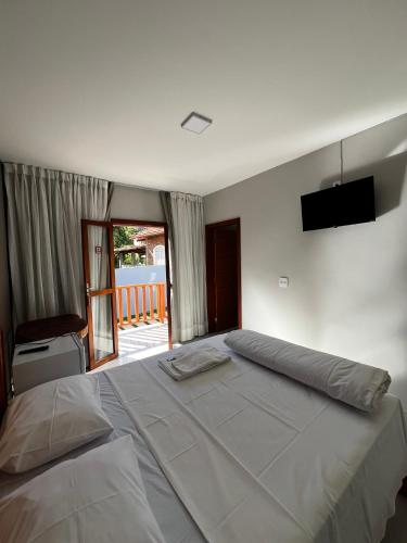 a bedroom with a large bed with a television on the wall at Pousada do Rui in Caparaó Velho