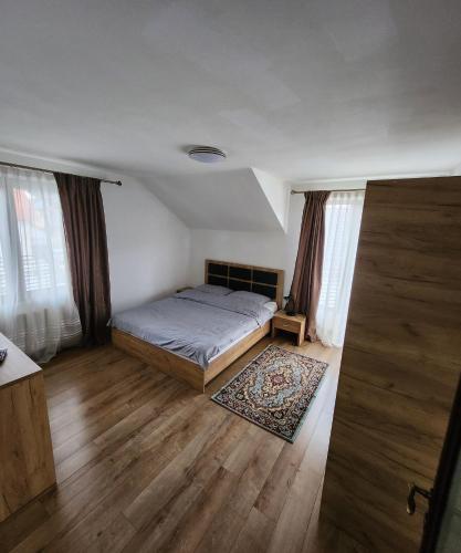 een slaapkamer met een bed en een houten vloer bij Casa CLO in Sighetu Marmaţiei
