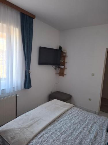 a bedroom with a bed and a flat screen tv at Studio apartman KONAK in Kupres