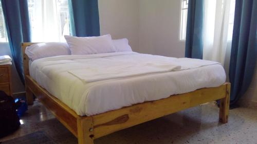Elle comprend un grand lit avec des draps et des oreillers blancs. dans l'établissement Gray Hideaway Resort, à Jinja