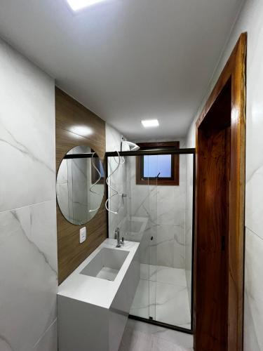 a white bathroom with a sink and a mirror at Pousada do Rui in Caparaó Velho