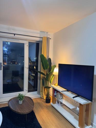 a living room with a large flat screen tv at 1 private room & a toilet in 2bed apartment in Manchester