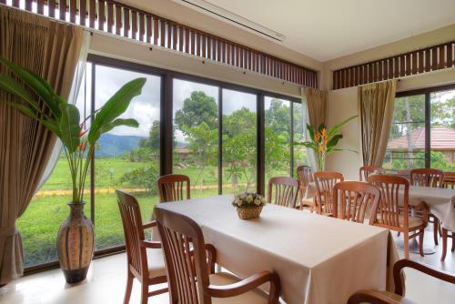 a dining room with tables and chairs and a large window at Sabaidee Valley in Ban Gnik