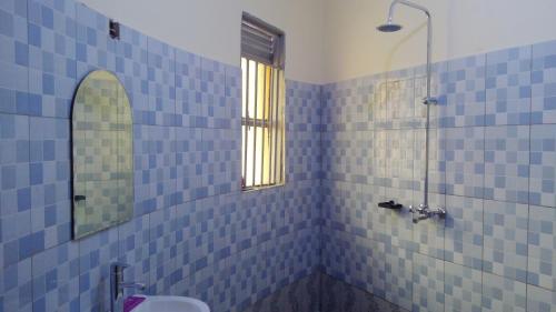 La salle de bains est pourvue de carrelage bleu, d'une douche et d'un lavabo. dans l'établissement Gray Hideaway Resort, à Jinja