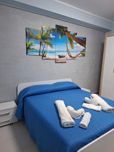 una camera da letto con un letto blu con palme e asciugamani di In Spiaggia a Mascali