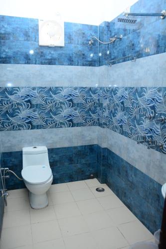 een badkamer met een toilet en een blauwe betegelde muur bij Krazy Hotel in Haldwani