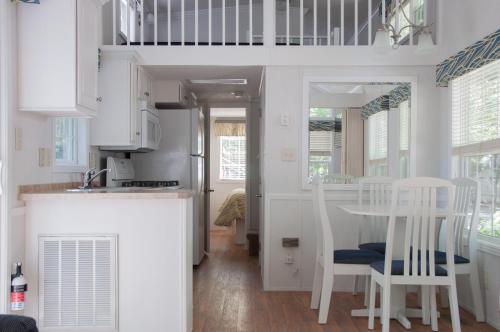 cocina con armarios blancos, mesa y sillas en Sea Pines Loft Cottage 7, en Swainton