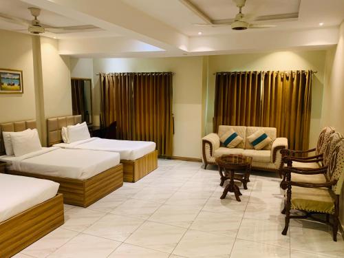 a hotel room with two beds and a table and chairs at Hotel pearlinn karachi in Karachi
