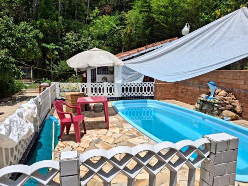 een zwembad met een tent en een tafel en stoelen bij Casa na mata ceu iluminado in Guararema