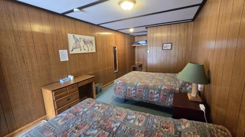 een hotelkamer met twee bedden en een bureau bij Black Cat Guest Ranch in Brule Mines