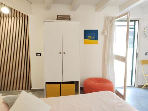 a bedroom with a white cabinet and a red chair at La casa tra le vie in Viagrande