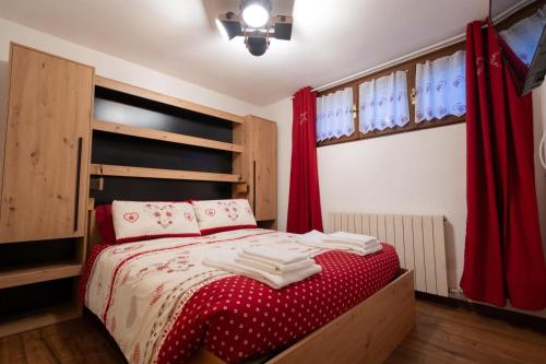 a bedroom with a bed with red sheets and red curtains at LAB Cottage in Madonna di Campiglio