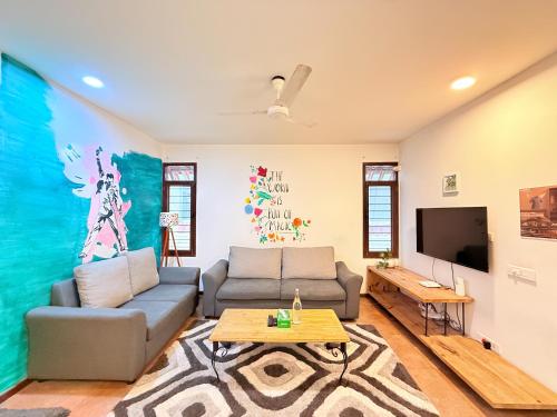 een woonkamer met een bank en een tv bij Jugglers Rest Boho Style 4BHK Spacez Luxury Villa with Terrace Lounge in Bangalore