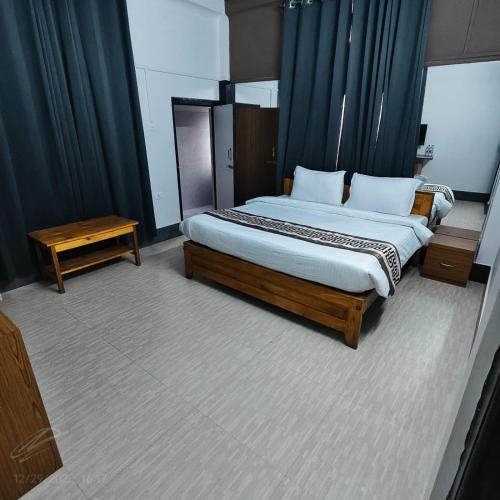 a bedroom with a large bed with blue curtains at Hotel ODC Residency in Jowai