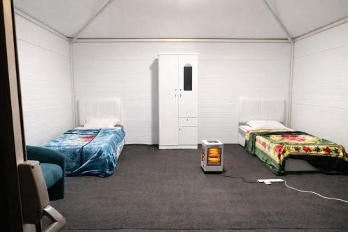 Zimmer mit 2 Betten und einem Herd in der Unterkunft خيم مبيت ملكية بالصياهد in Rumāḩ